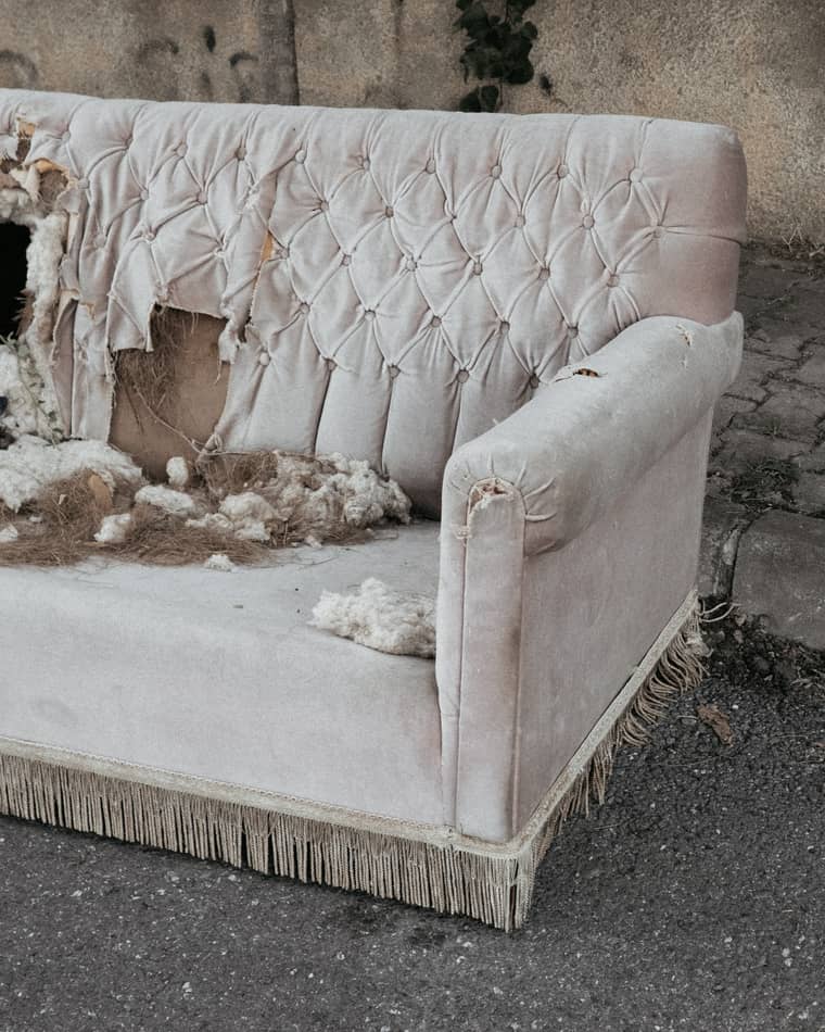 A worn out couch left at a curb.